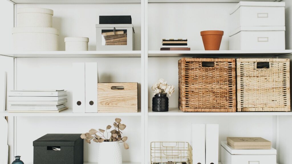 Organized shelving with baskets, storage boxes, and binders demonstrating a tidy space that may still feel unsettled or disconnected from how someone lives.