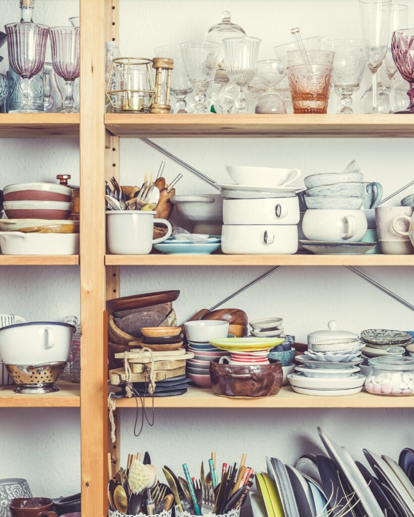 Cluttered kitchen shelves filled with dishes and glassware showing stagnant energy in your home