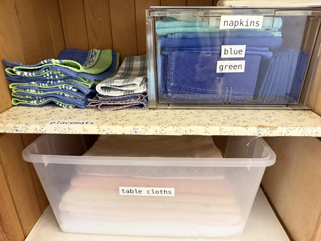 Labeled table linen storage system created during a home reset to improve accessibility and daily function.